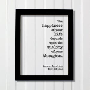 Op de afbeelding: Een zwarte rechthoekige lijst met een witte print met de zwarte tekst: The happiness of your life depends upon the quality of your thoughts. Marcus Aurelius Meditations. De letters zijn in een lettertype dat lijkt op een typemachine.