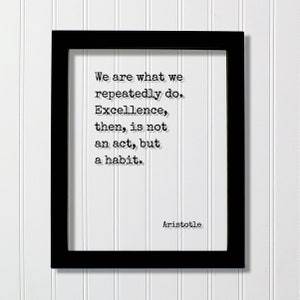 Op de afbeelding: Zwart ingelijst print met een witte achtergrond en een citaat van Aristoteles in zwarte tekst: "We zijn wat we herhaaldelijk doen. Uitmuntendheid is dan geen daad, maar een gewoonte."