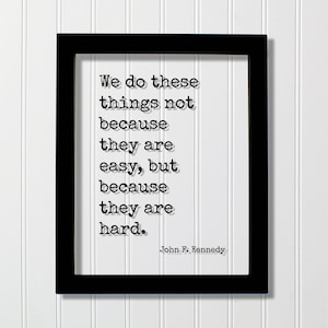May include: Black and white framed print with a quote by John F. Kennedy: "We do these things not because they are easy, but because they are hard."