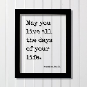 Op de afbeelding: Een zwarte rechthoekige lijst met een witte print met de zwarte tekst in typemachinestijl: May you live all the days of your life. De naam Jonathan Swift staat in de rechterbenedenhoek gedrukt in een kleiner lettertype in typemachinestijl.