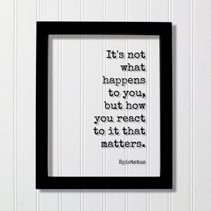 May include: Black framed print with a white background and black text that reads "It's not what happens to you, but how you react to it that matters. Epictetus."