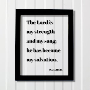 Puede incluir: Un marco rectangular negro que contiene un inserto blanco con el texto impreso en negro: The Lord is my strength and my song; he has become my salvation. Psalm 118:14. Las letras están en una fuente serif negrita con un ligero efecto de sombra.