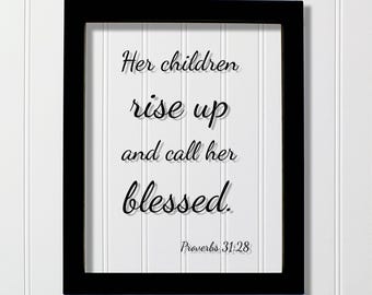 May include: A rectangular black frame containing a white insert with the black text: Her children rise up and call her blessed. Proverbs 31:28. The lettering is in a cursive script font, centered within the frame, and features a drop shadow effect.