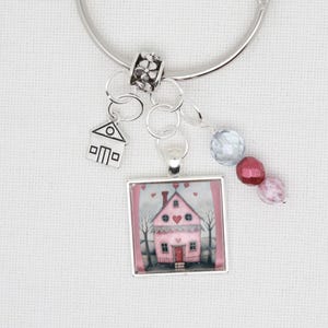 Peut inclure: Un bracelet à breloques argenté avec un charme de maison rose, des perles argentées et une perle de verre transparente et rose. Le charme de la maison a un cœur rouge sur la porte et des cœurs sur le toit.
