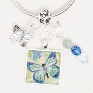 May include: Silver key ring with a blue butterfly charm, a silver butterfly charm, and blue and white glass beads.