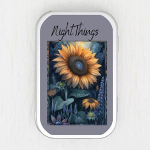 May include: A small, rectangular tin with a grey border and the words "Night Things" in black script. The tin features a watercolour painting of a sunflower and other flowers in a field.