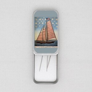 May include: A rectangular metal tin with a hinged lid, featuring a painting of a sailboat with red and white striped sails and an American flag. The background has a blue sky with white stars. The text "This land is your land" is at the bottom.
