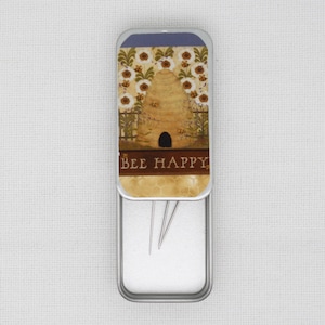 May include: A silver metal tin with a beehive and flowers design. The lid has the text "BEE HAPPY" and the tin contains sewing needles.
