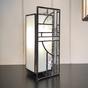 May include: A stained glass lamp with a white frosted glass shade and a geometric design. The lamp is made of metal and has a black finish.