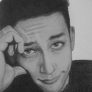 May include: A black and white pencil drawing of a person's face. The person is looking at the viewer with a slight smile. The person has short, dark hair and is wearing a dark shirt.