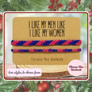 May include: Two handmade friendship bracelets featuring a pink, purple, and blue diagonal striped pattern. The bracelets are displayed on a tan card with the text I LIKE MY MEN LIKE I LIKE MY WOMEN and Florence Mae Handmade printed on it.