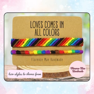 May include: Two rainbow friendship bracelets with the text "Loves comes in all colors" and "Florence Mae Handmade" on a brown card.