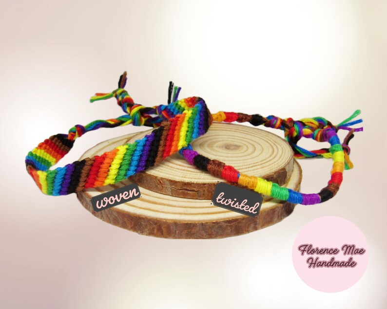 May include: Two rainbow-colored bracelets made of thread. One bracelet features a flat woven pattern with a black tag labeled "woven," while the other is a round twisted cord with a black tag labeled "twisted." A pink circle displays "Florence Mae Handmade."