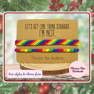 May include: Two rainbow-colored woven bracelets displayed on a rectangular tan card. The card features the black text: LET'S GET ONE THING STRAIGHT: I'M NOT. and Florence Mae Handmade. One bracelet has a diagonal pattern, the other a knotted design.