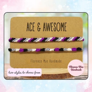 May include: Two handmade friendship bracelets with ace pride colors: black, gray, white, and purple. The bracelets are displayed on a brown card with the text "ACE & AWESOME" and "Florence Mae Handmade". The image also includes the text "two styles to choose from".