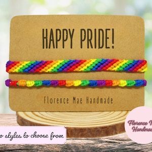 May include: Two rainbow friendship bracelets on a brown card with the text "HAPPY PRIDE!" and "Florence Mae Handmade".