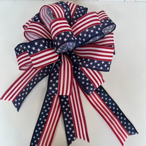 May include: A red, white, and blue bow with a star pattern. The bow is made of fabric and is tied in a traditional bow shape.