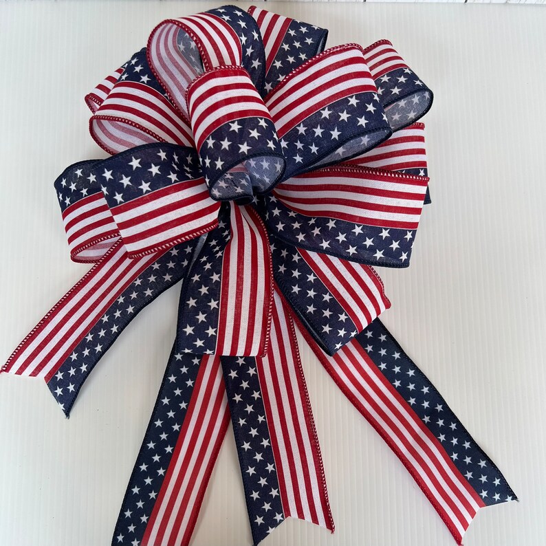 May include: A red, white, and blue bow with a star pattern. The bow is made of fabric and is tied in a traditional bow shape.