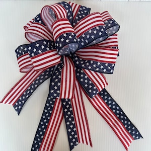 May include: A red, white, and blue bow with a star pattern. The bow is made of fabric and is tied in a traditional bow shape.