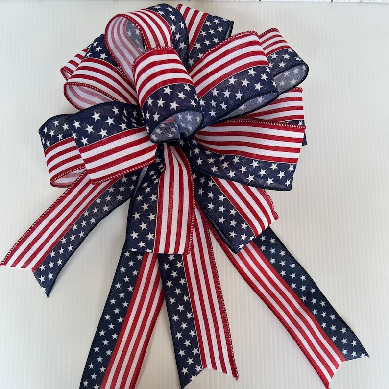 May include: A red, white, and blue bow with a star pattern. The bow is made of fabric and is tied in a traditional bow shape.