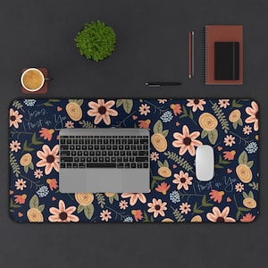 May include: A blue floral desk mat with a laptop, mouse, and the text "Jesus, I trust in You."  The mat has a variety of flowers in shades of pink, yellow, and orange.