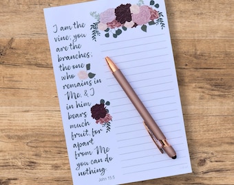 May include: A white notepad with a floral design and lined pages. The notepad features a quote from the Bible, John 15:5, "I am the vine, you are the branches; the one who remains in Me, & I in him bears much fruit, for apart from Me you can do nothing."