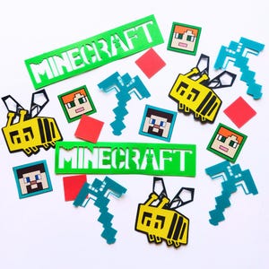 Peut inclure: Une collection de découpes en papier colorées représentant des personnages et des objets de Minecraft. Les découpes comprennent une pioche, une abeille, un creeper et le mot "Minecraft" en vert.