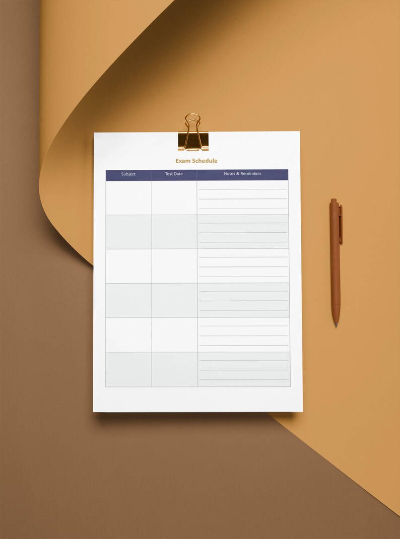Op de afbeelding: Een printbare examenschema-sjabloon met kolommen voor vak, datum van het examen en notities en herinneringen. De sjabloon staat op een wit vel papier met een gouden paperclip.