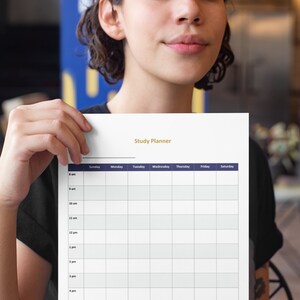 May include: A white study planner with a gold header that reads "Study Planner". The planner has a grid layout with time slots from 8 am to 8 pm and days of the week across the top.