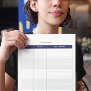 Op de afbeelding: Een wit printbaar examenrooster met de titel "Exam Schedule" in gouden letters. De tabel heeft kolommen voor vak, testdatum en notities en herinneringen. De tabel heeft een donkerblauwe kopregel.