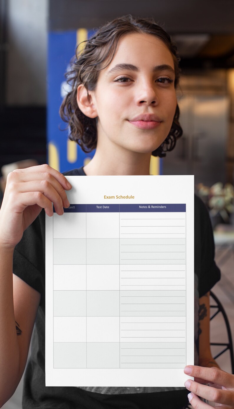 Op de afbeelding: Een wit printbaar examenrooster met de titel "Exam Schedule" in gouden letters. De tabel heeft kolommen voor vak, testdatum en notities en herinneringen. De tabel heeft een donkerblauwe kopregel.