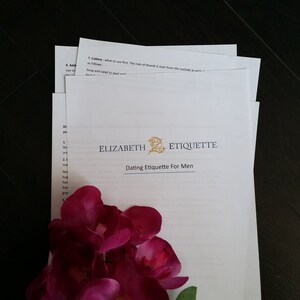 Puede incluir: Una hoja de papel blanca con el texto "ELIZABETH ETIQUETTE" y "Dating Etiquette For Men" impreso en dorado. El papel est&aacute; doblado por la mitad y tiene una flor rosa encima.