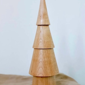 May include: A wooden Christmas tree ornament made of stacked cones. The tree is light brown and has a natural wood grain.