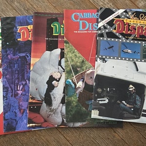 May include: A stack of five Cabbage Patch Kid magazines. The magazines are all different colors and have different pictures on the covers. The top magazine is a collector's edition and features a helicopter on the cover. The text on the cover reads "Collector's Edition Cabbage Patch Kid Dispatch".
