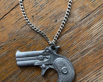 Vintage Derringer necklace. All metal. This item measures about 1.5 inches. Cool 1970’s piece! You need this. L@@K!