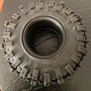 May include: Close-up of a black tire with the words "MUD SLINGERS" and "SCALE 1/4" printed on the side.