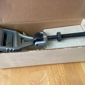 May include: A silver metal tool with a black roller and a long metal rod with a black nut. The tool is in a cardboard box.