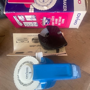 Vintage mint mini blue Dymo label maker in box 1970’s with one roll of labeling tape. The box shows wear and tear. You remember these! L@@K!
