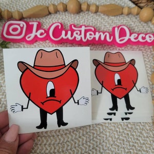 May include: Two red heart-shaped cartoon characters wearing cowboy hats and boots. The characters have a sad expression on their faces. The characters are printed on white sticker paper.