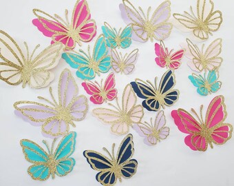 May include: A collection of 15 glitter butterfly cutouts in various colors, including pink, blue, teal, gold, and purple. The butterflies are made of paper and have a sparkly finish.