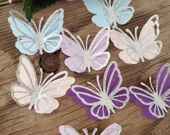 May include: A set of eight glittery butterfly cutouts in various pastel colors, including light blue, pink, purple, and lavender. The butterflies have a silver glitter finish and are perfect for adding a touch of whimsy to crafts, decorations, or party favors.
