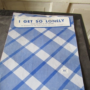 May include: A vintage sheet music cover with a blue and white checkered background. The title is "I Get So Lonely (Oh Baby Mine)" with the words and music credited to Pat Ballard. The sheet music is for a song recorded by The Four Knights for Capitol Records. The price is 50 cents. The publisher is Melrose Music Corp. located at 1619 Broadway, New York 19, N.Y.