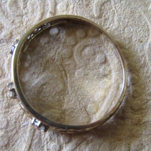 May include: A gold ring with small clear stones set into the band.