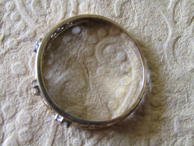 May include: A gold ring with small clear stones set into the band.