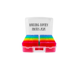 Op de afbeelding: Een doorzichtige plastic opbergkoffer met een wit handvat, gevuld met meerdere kleine, kleurrijke, doorschijnende fotodoosjes in twee rijen. De binnenkant van het deksel bevat de zwarte tekst Harding Family Photos 2020.