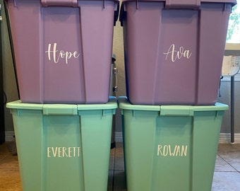 Op de afbeelding: Twee paarse plastic opbergbakken gestapeld op twee mintgroene plastic opbergbakken. De linker bovenbak bevat de witte tekst Hope, de rechter bovenbak de witte tekst Ava, de linker onderbak de witte tekst EVERETT en de rechter onderbak de witte tekst ROWAN.