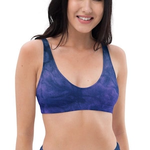 Op de afbeelding: Een bikini met een hoge taille en een tie-dye patroon in tinten paars en blauw. De bikini top heeft een ronde hals en dunne bandjes.