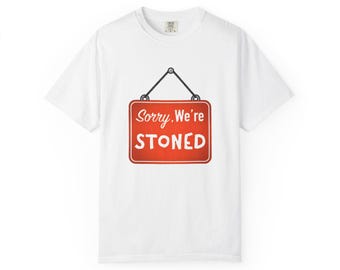 May include: White t-shirt with a red sign graphic that reads "Sorry, We're STONED." The sign is rectangular with rounded corners and is suspended by a black wire and two silver dots. The shirt is a basic crew neck.
