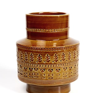 Könnte beinhalten: Eine braune Keramikvase mit geometrischem Muster. Die Vase hat einen breiten Boden und einen schmalen Hals.