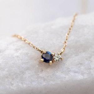 Blue sapphire and diamond necklace in cluster set for women. The stones are natural and the metal is 14K gold.